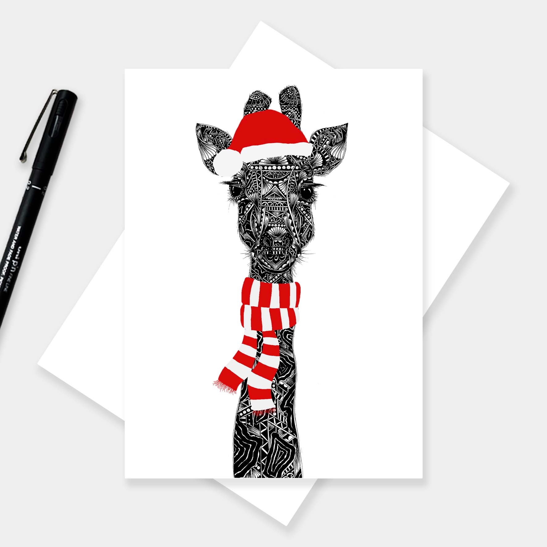 Christmas greeting card with a giraffe wearing a Santa hat and scarf on a white background