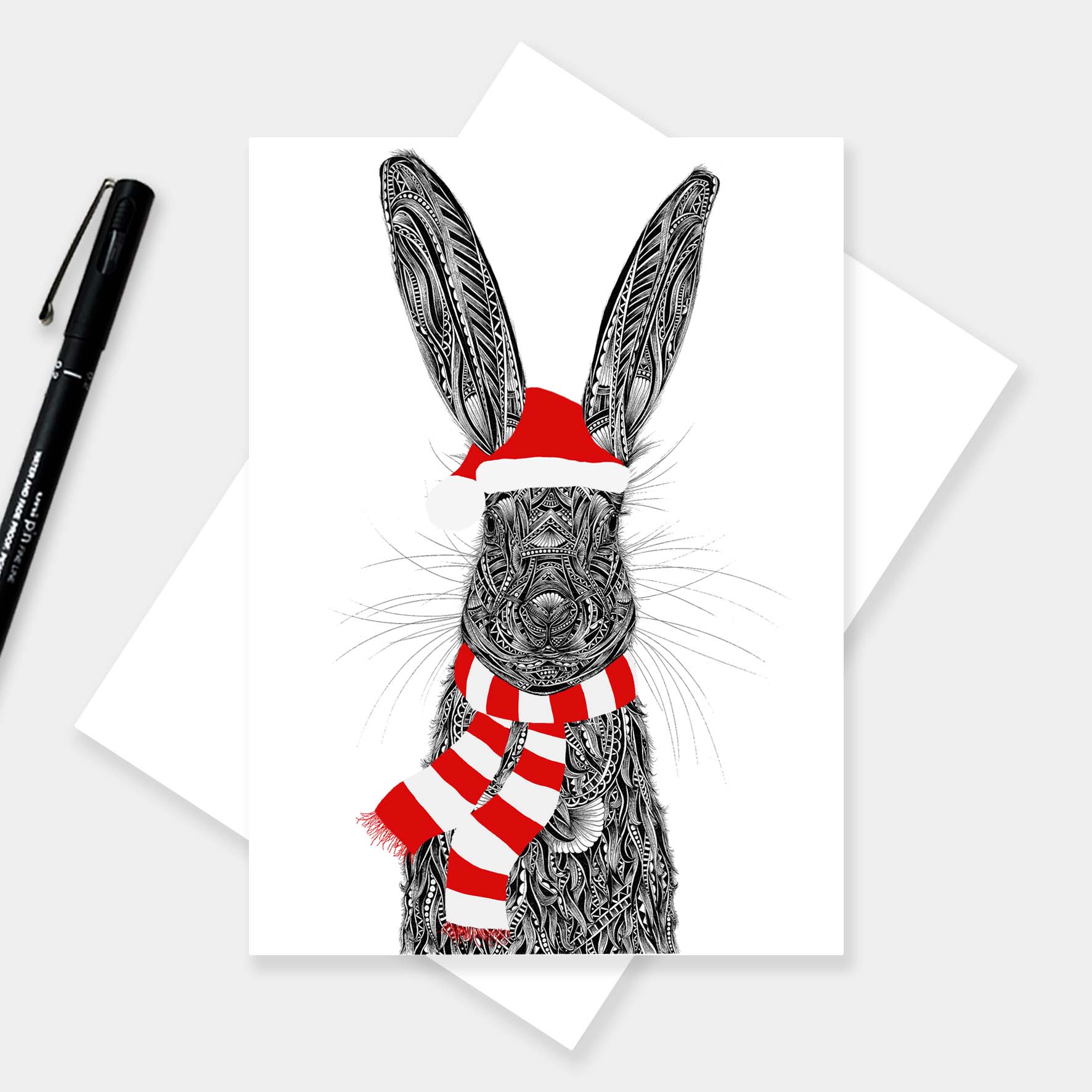 Christmas greeting card with a hare illustration wearing a red hat and scarf on a white background.