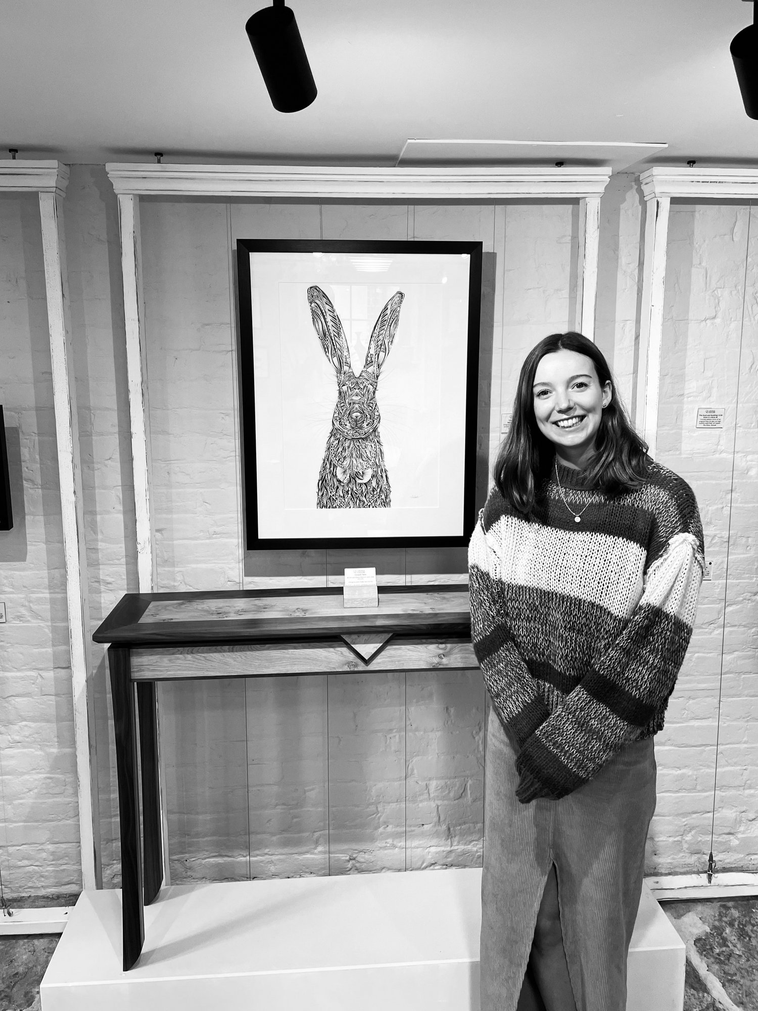 Pia Elliot standing in front of hand drawn, pen and ink Hare original artwork in Dorset gallery