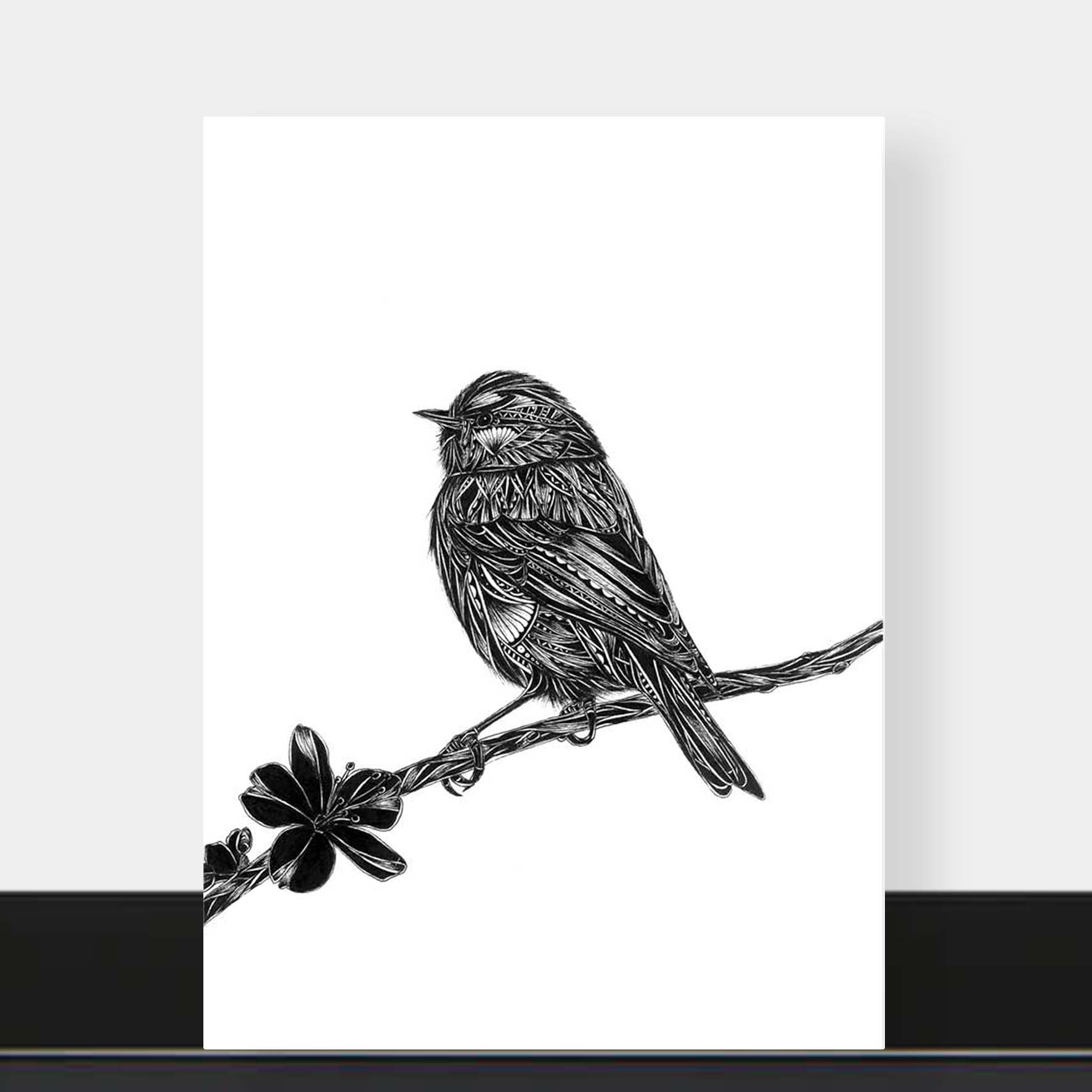 A vertical black and white art print featuring a detailed sketch of a bird perched on a branch with a flower, displayed against a light gray wall with a black baseboard.